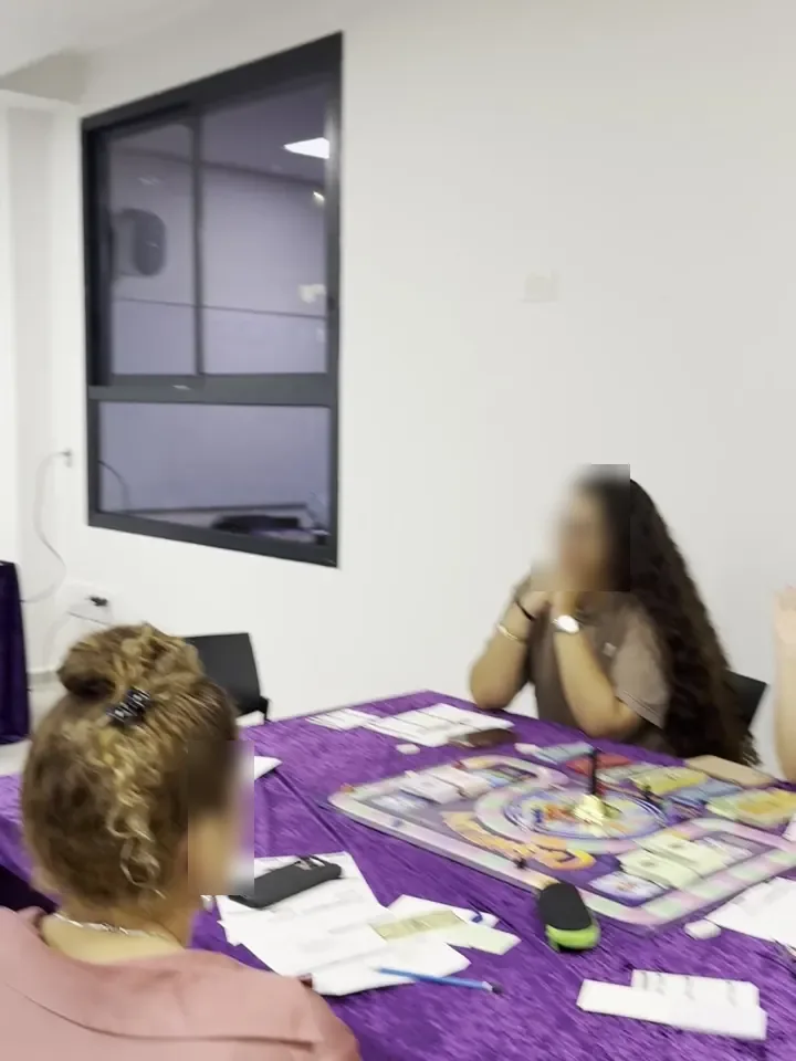 משתתפות משחקות ליד שולחן עם לוח המשחק והכרטיסים
